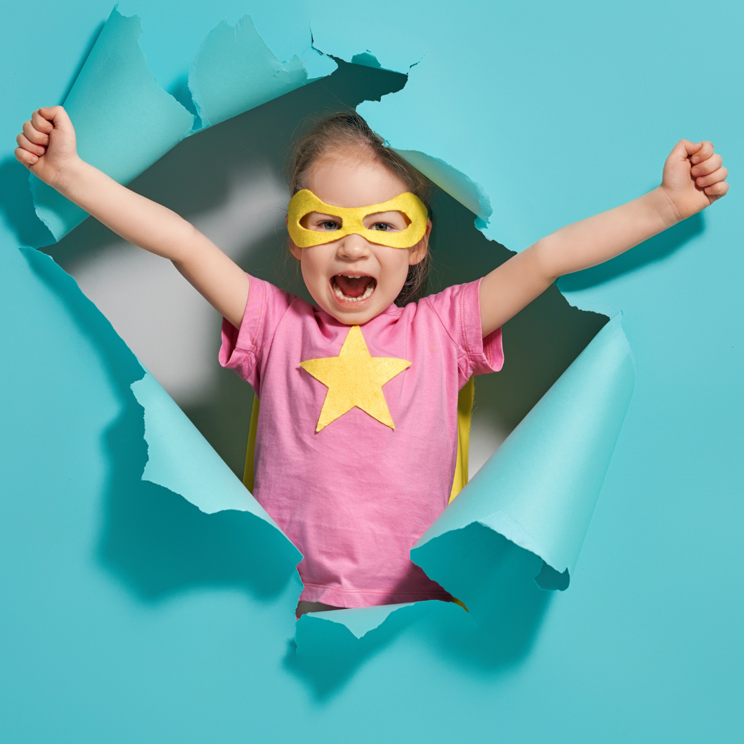 happy child dressed like a super hero, bursting through a paer wall